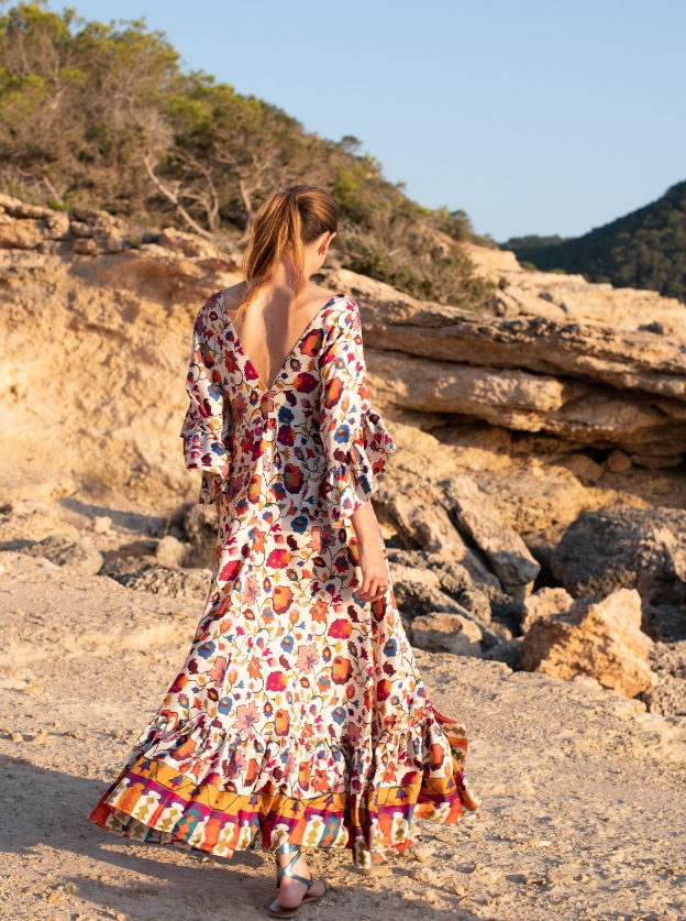 Woman wearing a printed sundress walking on the rocks in Ibiza